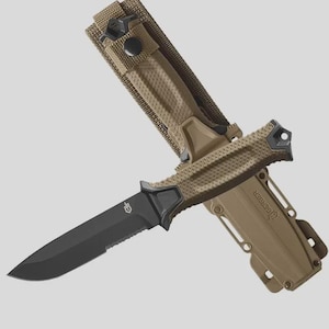 May include: A fixed-blade knife with a matte black drop-point blade and a textured tan handle. The knife is positioned over a matching tan sheath made of molded polymer and nylon webbing, featuring a black snap button and the Gerber brand logo.