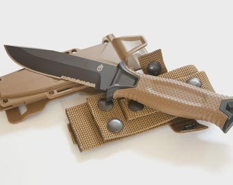Puede incluir: Un cuchillo de hoja fija con una hoja de acero negra parcialmente dentada y un mango beige texturizado. El cuchillo viene acompañado de una funda de plástico moldeado beige y una correa de nailon beige con botones de presión de metal oscuro.