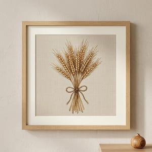 Könnte beinhalten: Ein quadratisches Wandbild mit einer detaillierten Kreuzstichstickerei einer goldenen Weizengarbe, die mit einer Schleife gebunden ist. Das Kunstwerk befindet sich auf einem hellbeigen Stoffhintergrund und ist in einem hellen Holzrahmen mit weißem Passepartout.