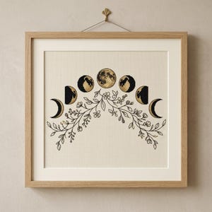 May include: A square framed cross-stitch embroidery featuring a lunar cycle depicted in black and gold thread. The moon phases are arranged in an arch above a symmetrical botanical design of black-stitched leaves and flowers on white fabric.