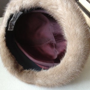 May include: A brown fur hat with a burgundy satin lining. The hat has a label that reads "My Furrier".