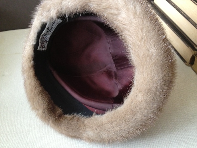 May include: A brown fur hat with a burgundy satin lining. The hat has a label that reads "My Furrier".