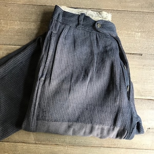 May include: A pair of dark blue striped pants with a button fly and a single back pocket. The pants have a faded look and are made of a thick, textured fabric.