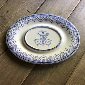 Puede incluir: Un plato ovalado blanco para servir con un diseño floral azul y blanco. El plato tiene un plato ovalado más pequeño en el centro con un monograma azul y blanco.