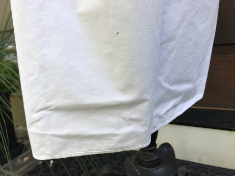 May include: White cotton fabric with a slight wrinkle. The fabric is smooth and has a slight sheen.