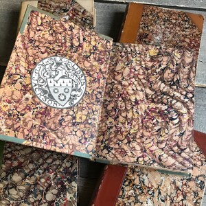 May include: Close-up of the cover of a book with a marbled paper design in shades of brown, red, and black. The book has a decorative crest with the text "Ex Libris" and "Jackson" on it.