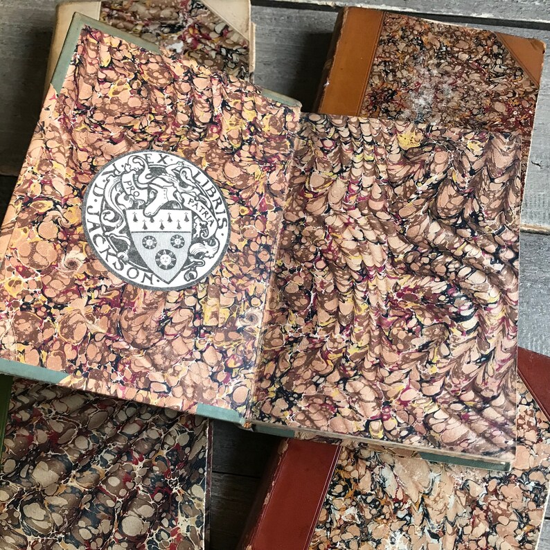 May include: Close-up of the cover of a book with a marbled paper design in shades of brown, red, and black. The book has a decorative crest with the text "Ex Libris" and "Jackson" on it.