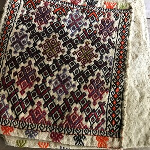 May include: A close-up of a beige fabric with a colorful geometric pattern. The fabric is folded in half and the pattern is visible on both sides.