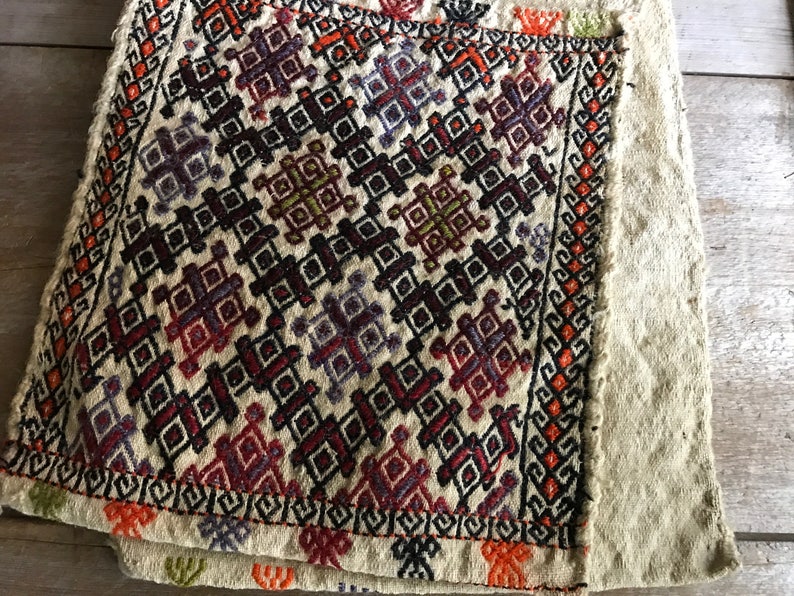 May include: A close-up of a beige fabric with a colorful geometric pattern. The fabric is folded in half and the pattern is visible on both sides.