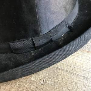 May include: A black bowler hat with a black grosgrain ribbon band.