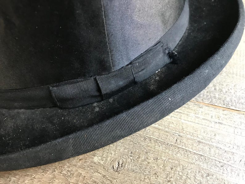 May include: A black bowler hat with a black grosgrain ribbon band.