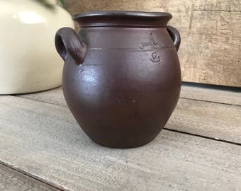Puede incluir: Una olla de barro marrón oscuro con dos asas y una inscripción estampada que dice "HOGAN & CO."
