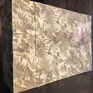 May include: A vintage wooden box with a floral pattern on the lid. The box is made of wood and has a distressed finish. The floral pattern is in shades of brown and cream.