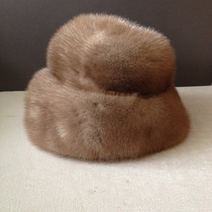 May include: A brown fur hat with a wide brim. The hat is made of soft, fluffy fur and has a simple, classic design.