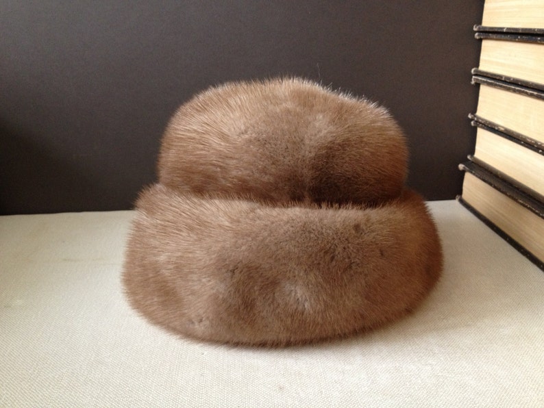 May include: A brown fur hat with a wide brim. The hat is made of soft, fluffy fur and has a simple, elegant design.