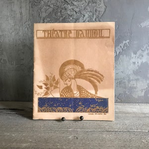 May include: A vintage program for the Theatre D'Art, featuring a stylized illustration of a woman in a headdress and a blue and gold patterned background.