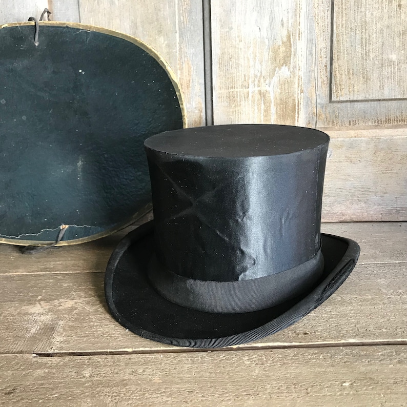 May include: A black top hat with a wide brim and a smooth, shiny finish. The hat is made of a sturdy material and has a classic design.