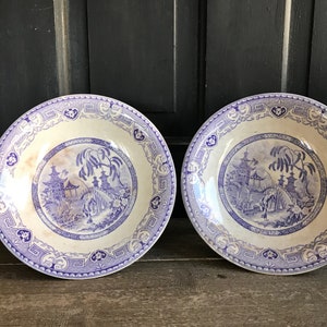 Puede incluir: Dos cuencos de porcelana vintage azul y blanco con un diseño de inspiración china. Los cuencos presentan una pagoda, un puente y árboles en un patrón azul y blanco.