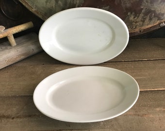 May include: Two white oval ceramic serving platters. The platters are plain white with no design or pattern.