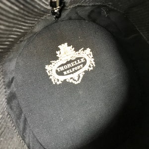 May include: The inside of a black hat with a white label that reads "THORELLE BELFORT".