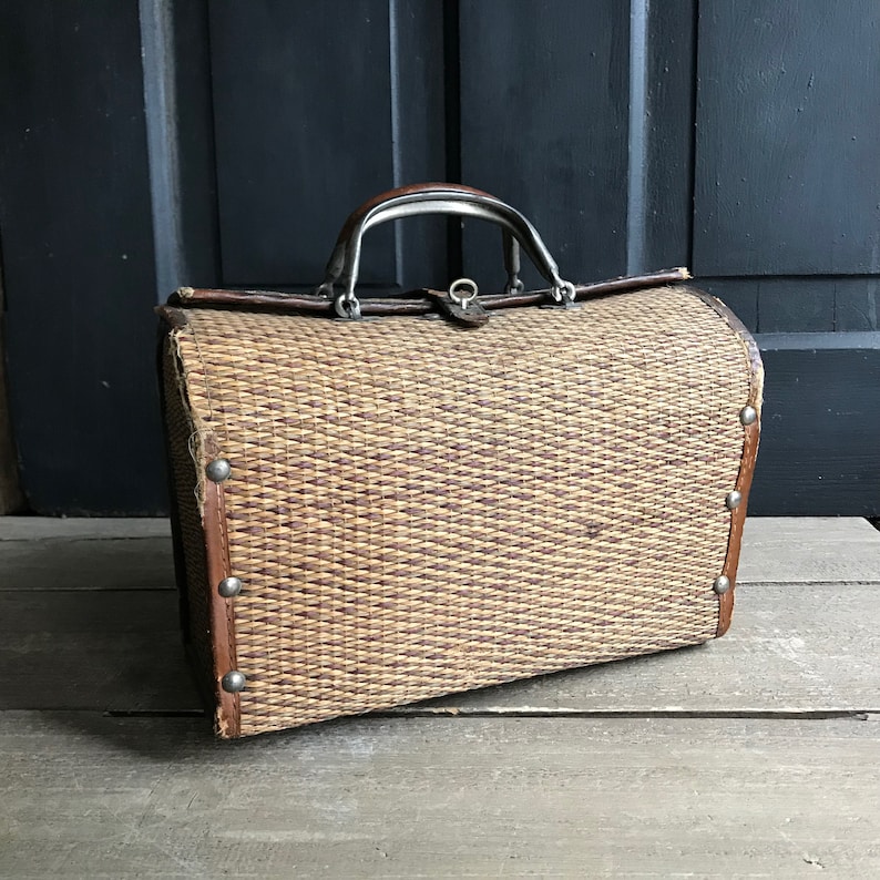 May include: A vintage woven wicker suitcase with a brown leather trim and a silver metal handle.