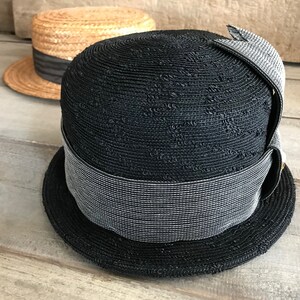 May include: A black straw hat with a wide brim and a gray ribbon. The hat has a textured woven design.