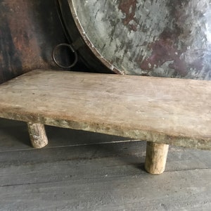 May include: A rustic wooden serving tray with a rectangular top and three legs. The tray is made of natural wood and has a weathered finish.