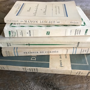 May include: A stack of five vintage paperback books with French titles. The top book is white with green text and the title "Prévost Manon Lescaut". The second book is white with green text and the title "La Cravache". The third book is white with green text and the title "Mickel Deal". The fourth book is white with blue and green text and the title "Premier de Cordée". The bottom book is blue with white text and the title "Frison Roche".