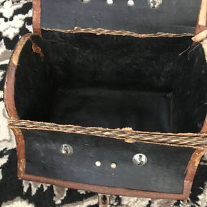 May include: A vintage brown leather satchel with a black interior and metal clasps. The satchel is open and the interior is visible.