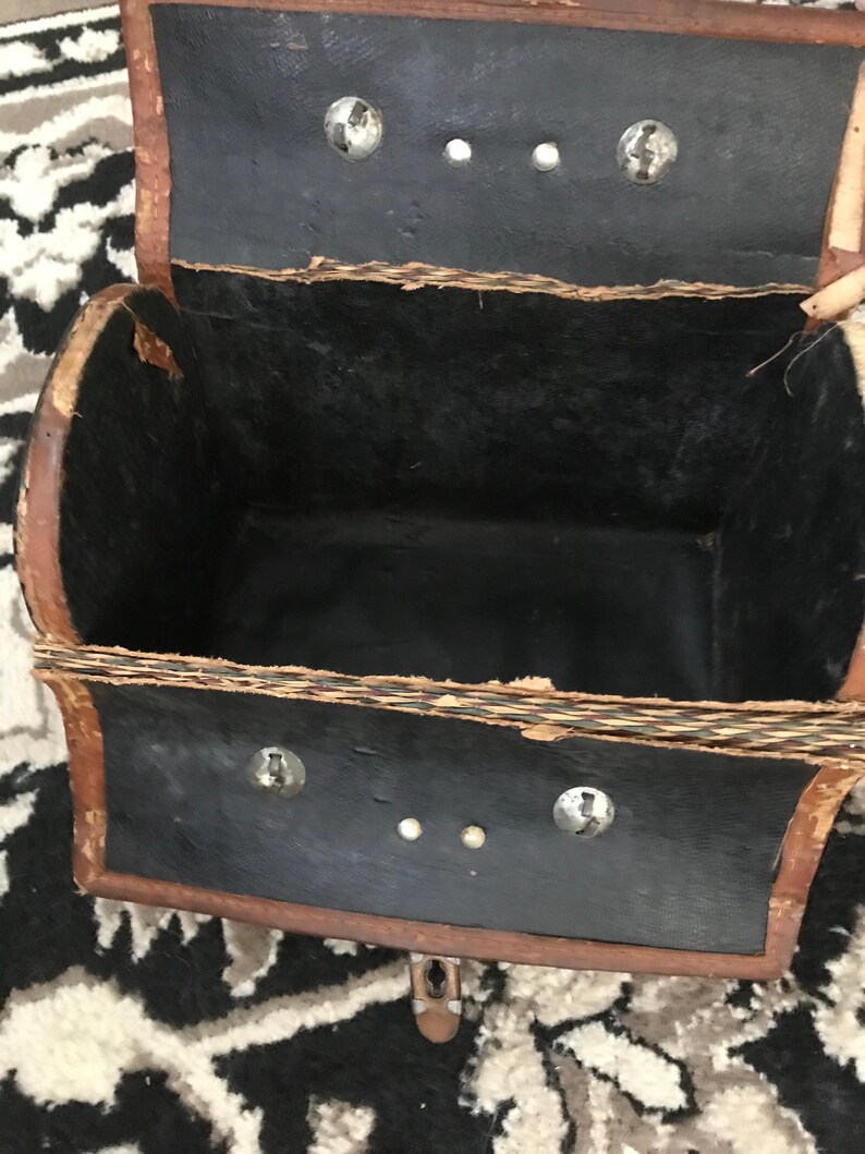 May include: A vintage brown leather satchel with a black interior and metal clasps. The satchel is open and the interior is visible.