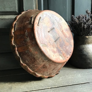 May include: An antique wooden bowl with a scalloped edge, in a warm reddish-brown hue. The bowl shows visible nail heads and aged wood grain. It is displayed on a weathered wooden surface, evoking a vintage feel. The bowl is likely of European origin.
