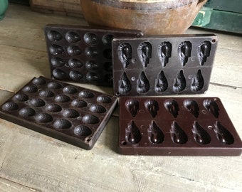 May include: Four vintage brown plastic chocolate molds. Two molds are for making egg-shaped chocolates, and two molds are for making shrimp-shaped chocolates.