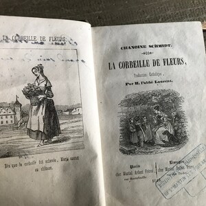 May include: A vintage book titled "La Corbeille de Fleurs" by Chanoine Schmidt. The book cover features a black and white illustration of a woman carrying a basket of flowers. The book is published by Martial Ardant Fr&egrave;res in Paris and Limoges.