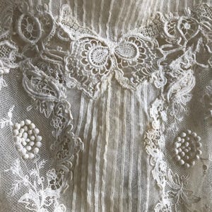 May include: White lace fabric with a delicate floral pattern. The fabric is sheer and has a soft, romantic feel.