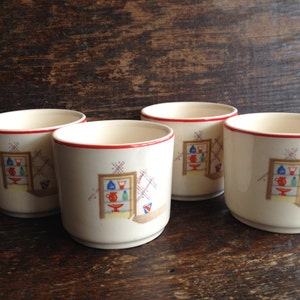 May include: Set of four white ceramic mugs with a red rim. Each mug features a colorful illustration of a shelf with various bottles and jars.