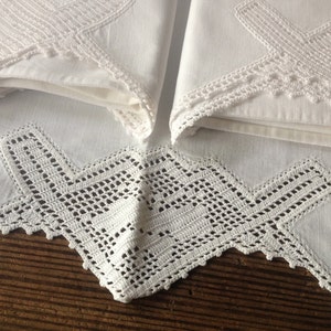 May include: Two white cotton pillowcases with delicate crocheted lace trim. The lace features a geometric pattern with a scalloped edge.