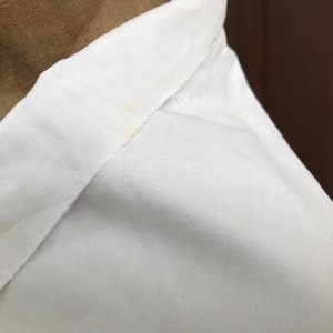 May include: White linen shirt collar with a small yellow stain.