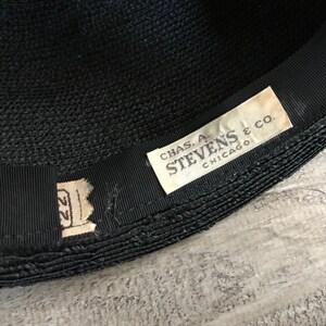 May include: A black woven hat with a black ribbon and a white label that reads "CHAS. A. STEVENS & CO. CHICAGO".