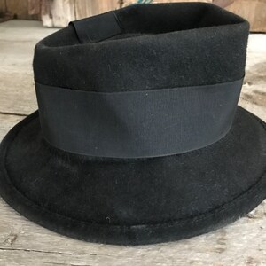 以下が含まれることがあります： 幅広のつばと黒いグログランリボンバンドが付いた、黒いフェルトのフェドラハットです。