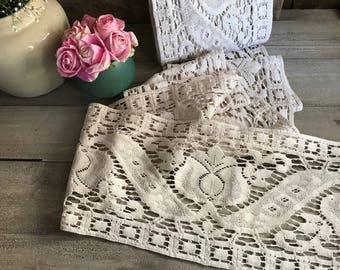 Könnte beinhalten: Nahaufnahme einer weißen Häkelspitze mit einem zarten Blumenmuster. Die Spitze ist in mehreren Schichten angeordnet, was einen strukturierten und eleganten Look erzeugt.