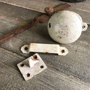 May include: A set of four antique white metal door hardware pieces. The set includes a door handle, a door latch, a door knob, and a door stop.