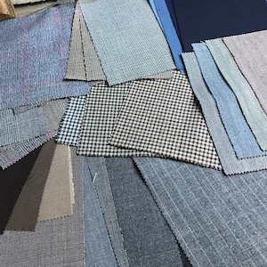 May include: A collection of fabric swatches in various colors and patterns, including blue, brown, gray, and white. The swatches are arranged in a random pattern on a light brown surface.