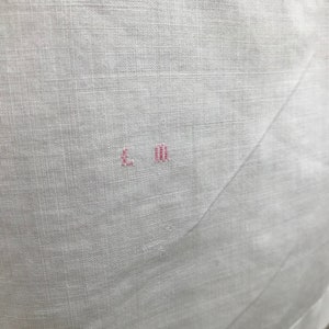 May include: White linen fabric with a small pink embroidered mark that reads "L.M."