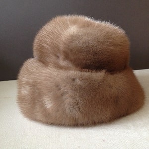 May include: A brown fur hat with a wide brim. The hat is made of soft, fluffy fur and has a simple, classic design.