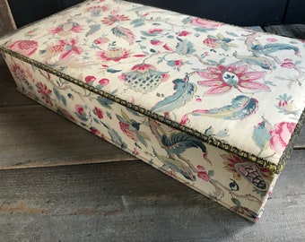 May include: A vintage floral patterned box with a gold trim. The box is made of fabric and has a rectangular shape.