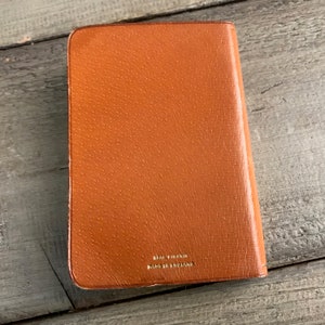May include: A brown leather journal with the text "Real  VirsKin Made in England" embossed in gold on the back cover.