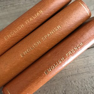 May include: Three leather-bound books with gold lettering. The titles are "English Italian", "English Spanish", and "English French".