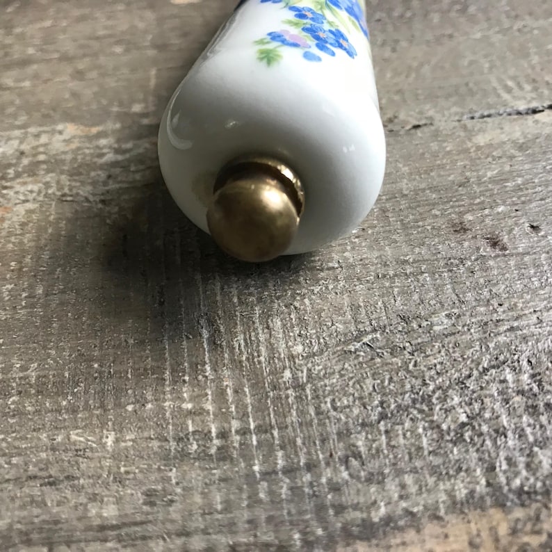 May include: White ceramic bottle stopper with a floral design and a gold metal top.