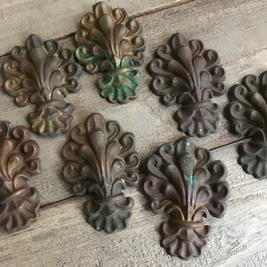 May include: Eight ornate metal decorative pieces with a floral design. The pieces are in shades of gold, brown, and green.