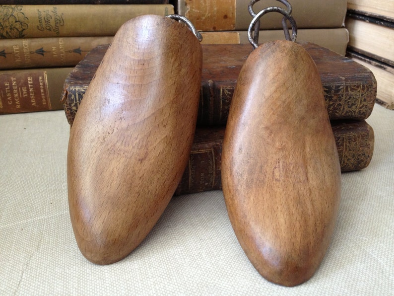 May include: Two wooden shoe trees with metal hooks. The shoe trees are brown and have a smooth finish.